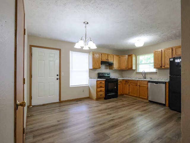 1324 N Forest Ave, Springfield, MO 65802 - kitchen with black appliances, under cabinet range hood, light countertops, a chandelier, and a textured ceiling