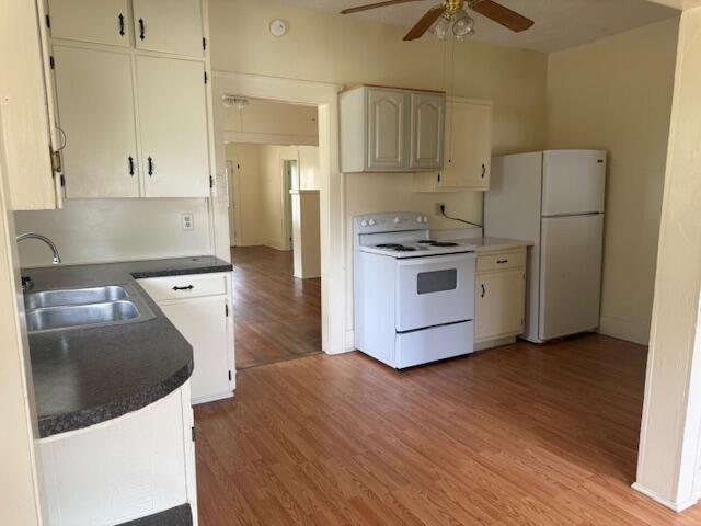 714 W Leyda Ave, West Plains, MO 65775 - kitchen with white appliances, a ceiling fan, light wood-style flooring, dark countertops, and white cabinets