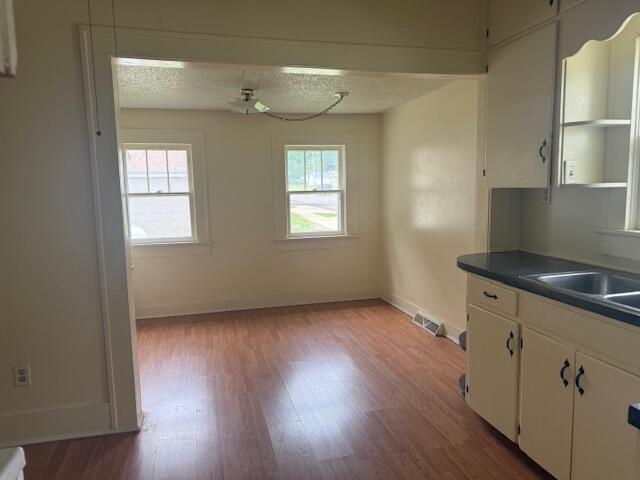714 W Leyda Ave, West Plains, MO 65775 - kitchen with plenty of natural light, white cabinets, wood finished floors, dark countertops, and a textured ceiling