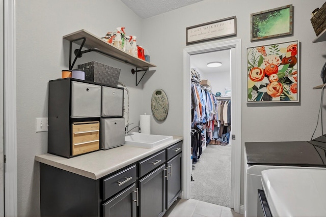 4050 W Page Pl, Springfield, MO 65802 - laundry area featuring washer and dryer, cabinet space, light tile patterned floors, light colored carpet, and a textured ceiling