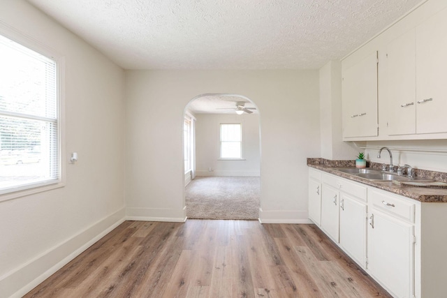 1921 W Atlantic St, Springfield, MO 65803 - kitchen featuring a textured ceiling, arched walkways, white cabinetry, light wood-style floors, and dark countertops
