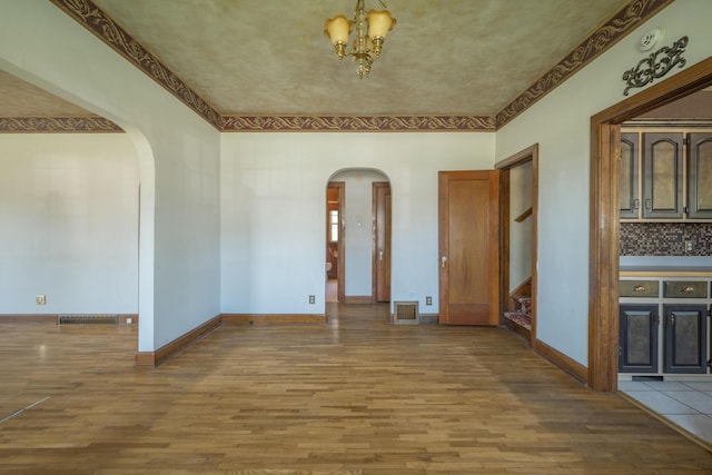 400 S Jefferson St, Neosho, MO 64850 - unfurnished dining area featuring arched walkways, wood finished floors, a chandelier, stairs, and crown molding