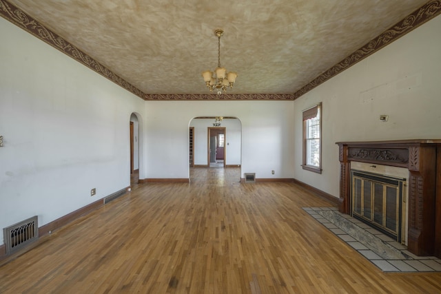 400 S Jefferson St, Neosho, MO 64850 - unfurnished living room featuring arched walkways, a chandelier, wood finished floors, a tile fireplace, and crown molding