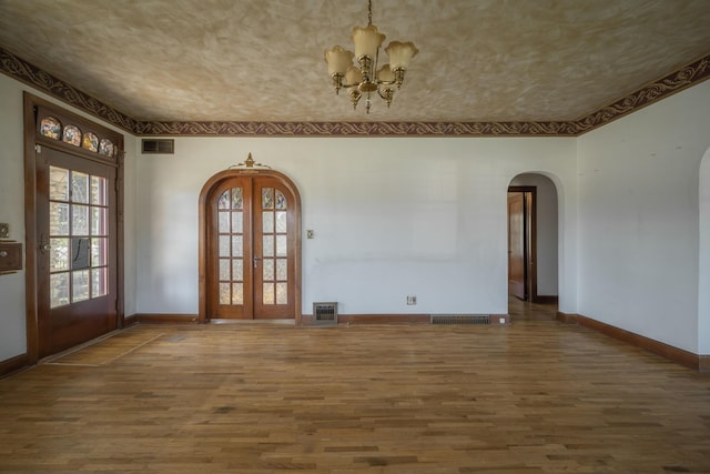 400 S Jefferson St, Neosho, MO 64850 - empty room featuring arched walkways, a chandelier, plenty of natural light, and wood finished floors