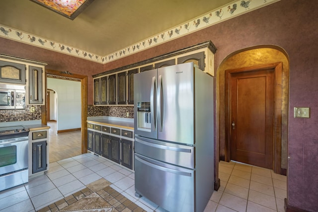 400 S Jefferson St, Neosho, MO 64850 - kitchen featuring stainless steel appliances, arched walkways, light tile patterned flooring, and decorative backsplash