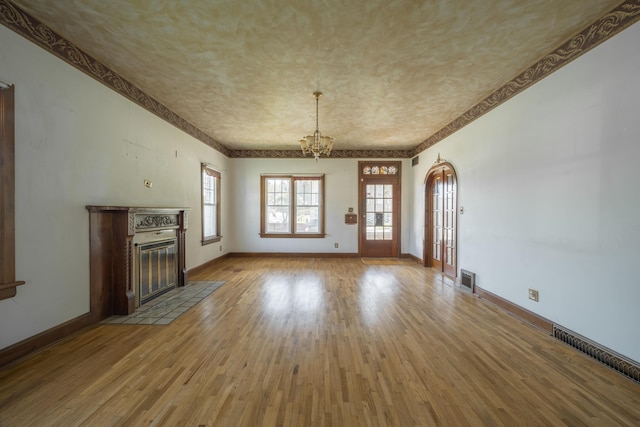 400 S Jefferson St, Neosho, MO 64850 - unfurnished living room with a chandelier, a fireplace with flush hearth, wood finished floors, arched walkways, and a textured ceiling