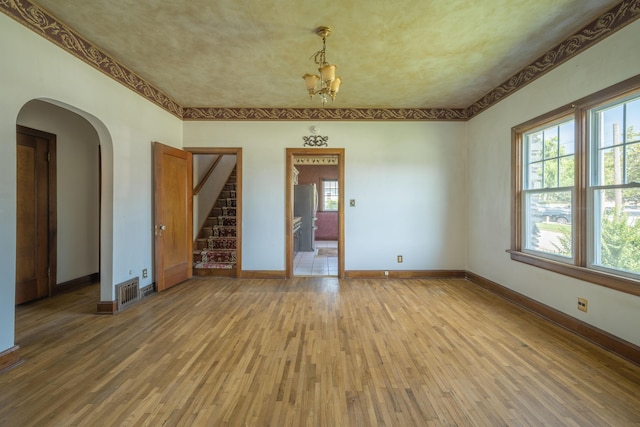 400 S Jefferson St, Neosho, MO 64850 - unfurnished room featuring light wood-type flooring, stairs, arched walkways, and a chandelier