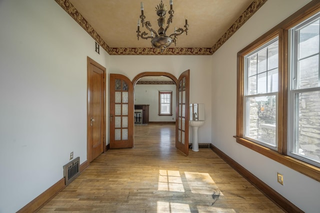 400 S Jefferson St, Neosho, MO 64850 - hallway featuring french doors, wood finished floors, a chandelier, and arched walkways