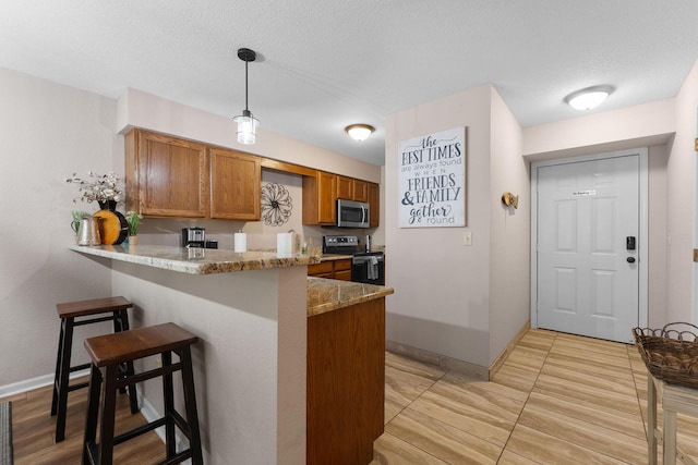 366 Wimbledon Dr Unit 4, Branson, MO 65616 - kitchen with stainless steel appliances, brown cabinetry, a peninsula, a kitchen bar, and light stone countertops