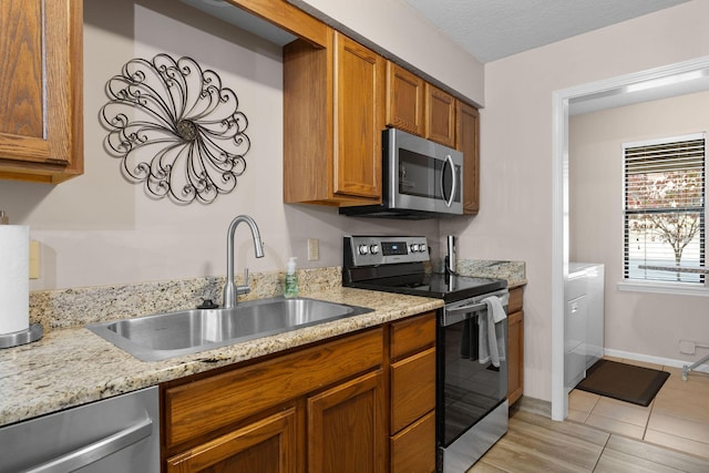 366 Wimbledon Dr Unit 4, Branson, MO 65616 - kitchen with appliances with stainless steel finishes, brown cabinetry, light tile patterned floors, and light stone counters