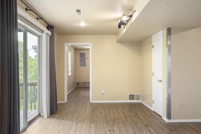 1813 Boswell Ave, Branson, MO 65616 - empty room featuring a textured ceiling, light wood-style flooring, electric panel, and plenty of natural light