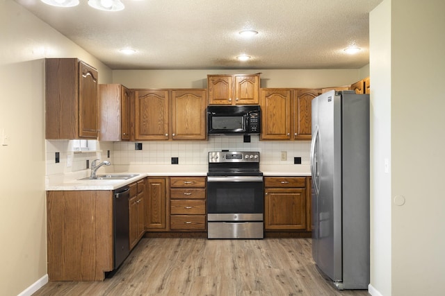 1813 Boswell Ave, Branson, MO 65616 - kitchen with appliances with stainless steel finishes, brown cabinets, light wood-style floors, decorative backsplash, and a textured ceiling