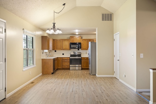 1813 Boswell Ave, Branson, MO 65616 - kitchen with stainless steel appliances, brown cabinetry, light countertops, a chandelier, and backsplash