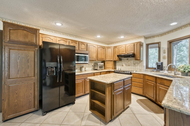 636 Crader Ct, Springfield, MO 65802 - kitchen featuring black refrigerator with ice dispenser, stainless steel microwave, under cabinet range hood, light stone counters, and a textured ceiling