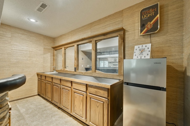 636 Crader Ct, Springfield, MO 65802 - kitchen with freestanding refrigerator, a textured ceiling, light colored carpet, and brown cabinetry