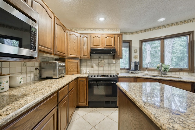 636 Crader Ct, Springfield, MO 65802 - kitchen with stainless steel microwave, black / electric stove, under cabinet range hood, a textured ceiling, and decorative backsplash