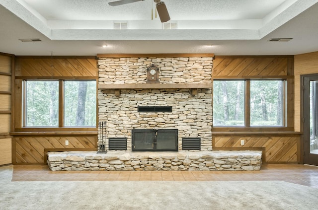 636 Crader Ct, Springfield, MO 65802 - unfurnished living room featuring a stone fireplace, wood walls, a raised ceiling, a ceiling fan, and tile patterned flooring