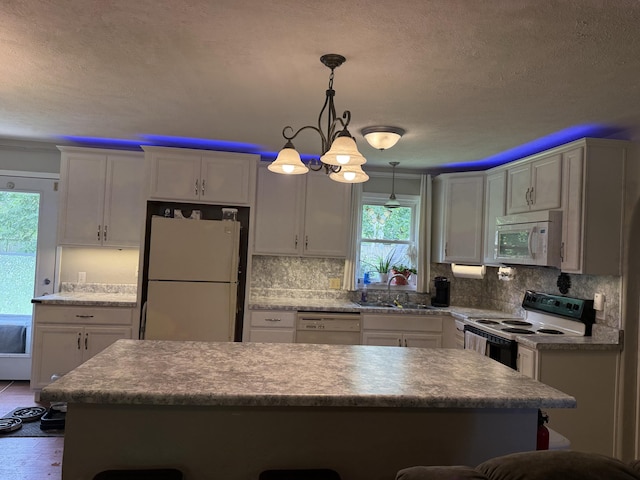 2304 E Huntington St, Ozark, MO 65721 - kitchen featuring white appliances, a breakfast bar area, decorative backsplash, a textured ceiling, and decorative light fixtures