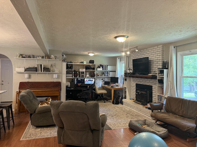 2304 E Huntington St, Ozark, MO 65721 - living room with a textured ceiling, wood finished floors, arched walkways, track lighting, and a fireplace