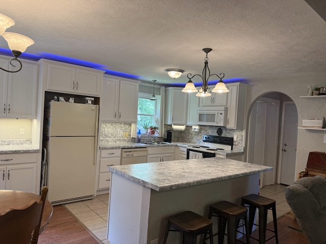 2304 E Huntington St, Ozark, MO 65721 - kitchen featuring white appliances, decorative backsplash, light countertops, a textured ceiling, and a kitchen bar