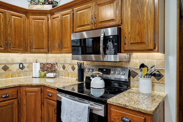 3449 S Woodstock Dr, Springfield, MO 65809 - kitchen featuring appliances with stainless steel finishes, brown cabinets, tasteful backsplash, and light stone counters
