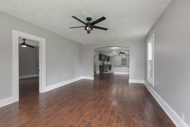 720 W Mount Vernon St, Springfield, MO 65806 - unfurnished living room with a ceiling fan, dark wood-style floors, arched walkways, and a textured ceiling