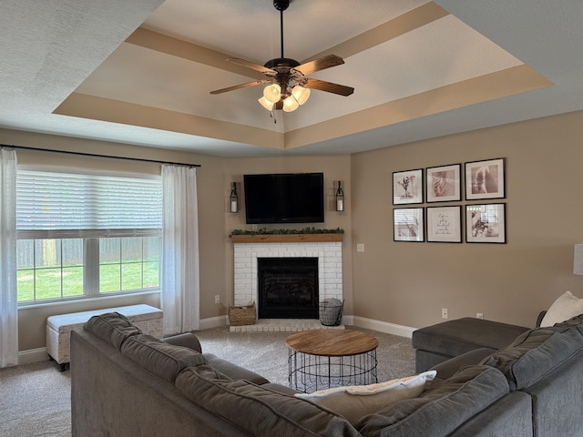 1129 S Erika Ave, Springfield, MO 65802 - living room featuring a raised ceiling, carpet floors, a ceiling fan, and a brick fireplace