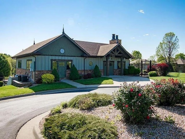 1129 S Erika Ave, Springfield, MO 65802 - view of front of home with board and batten siding, a chimney, and stone siding