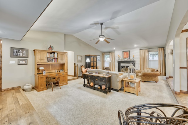 1820 E Jacqueline St, Springfield, MO 65804 - living room with a ceiling fan, vaulted ceiling, light wood finished floors, a fireplace, and arched walkways