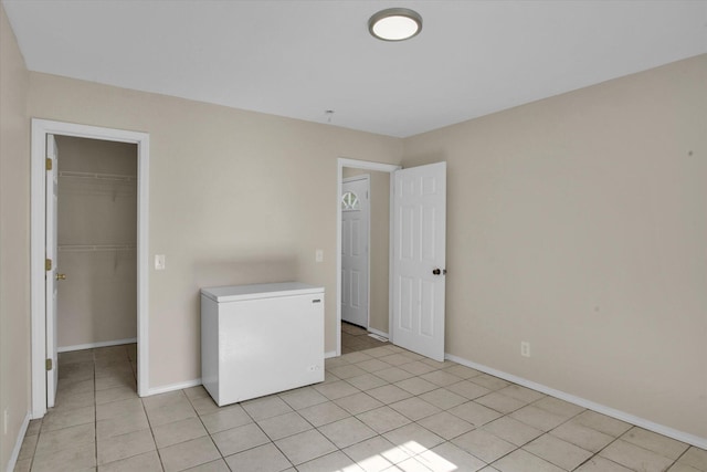 2431 N Kellett Ave, Springfield, MO 65803 - unfurnished bedroom with white fridge, light tile patterned flooring, a walk in closet, and a closet