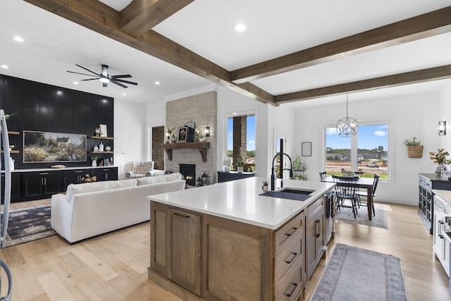 858 E Edenmore Cir, Nixa, MO 65714 - kitchen with a fireplace, light wood finished floors, beamed ceiling, light countertops, and an island with sink