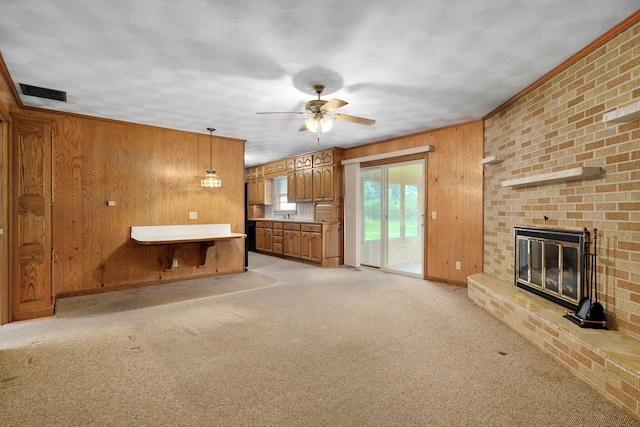 3066 E Lomita St, Springfield, MO 65804 - unfurnished living room featuring wood walls, a ceiling fan, a brick fireplace, and light carpet