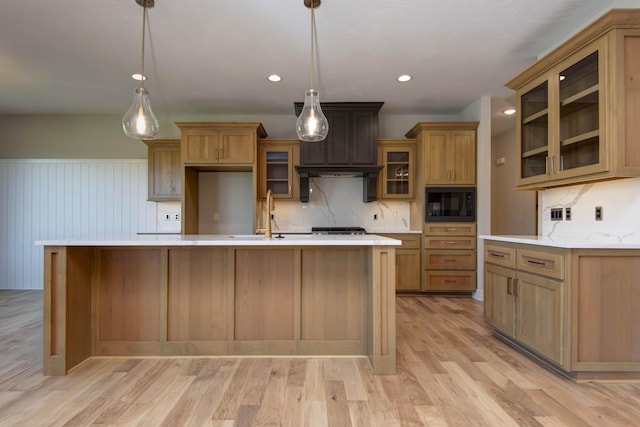 6059 S Clay Ave, Springfield, MO 65810 - kitchen with black microwave, light countertops, light wood finished floors, a large island, and decorative backsplash