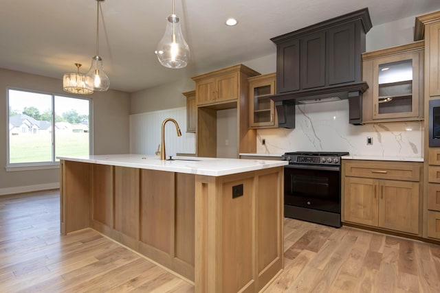 6059 S Clay Ave, Springfield, MO 65810 - kitchen featuring stainless steel range with electric cooktop, decorative backsplash, light wood-style floors, a kitchen island with sink, and glass insert cabinets