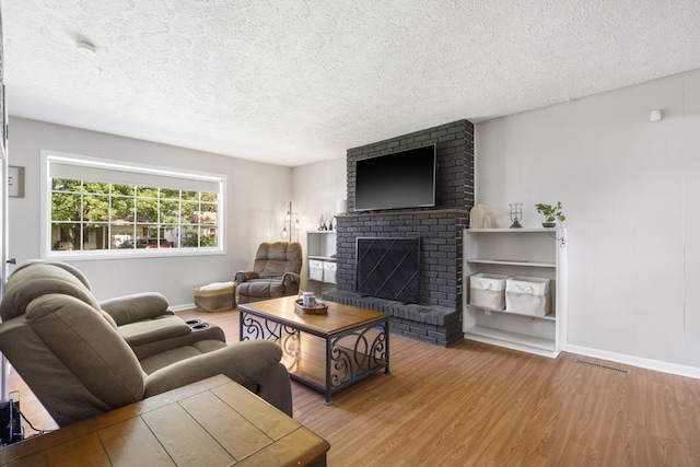 2558 S Nettleton Ave, Springfield, MO 65807 - living room featuring wood finished floors, a brick fireplace, and a textured ceiling