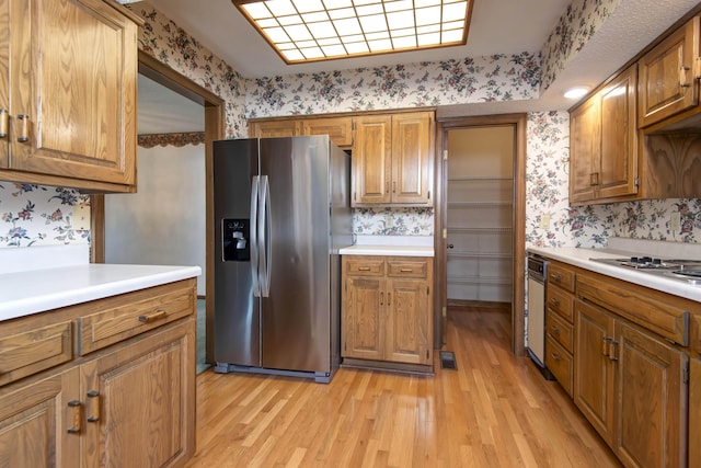 3501 E Cooper Blvd, Springfield, MO 65802 - kitchen with stainless steel fridge, wallpapered walls, light wood-type flooring, brown cabinets, and stovetop