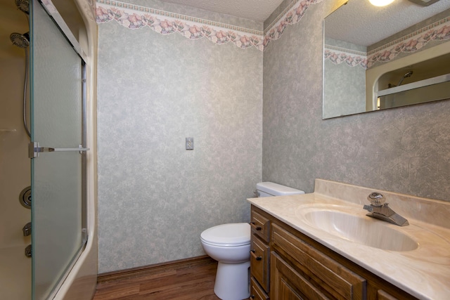 3501 E Cooper Blvd, Springfield, MO 65802 - bathroom with wood finished floors, wallpapered walls, vanity, a textured ceiling, and combined bath / shower with glass door