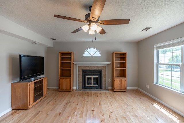 2981 W Highpoint St, Springfield, MO 65810 - unfurnished living room with hardwood / wood-style floors, healthy amount of natural light, a textured ceiling, a tile fireplace, and ceiling fan
