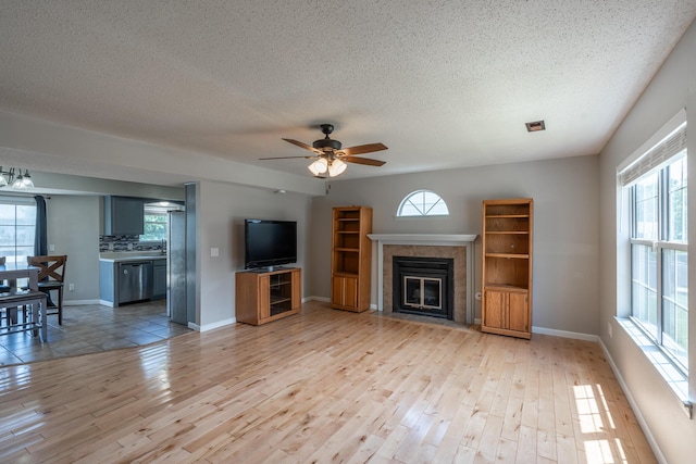 2981 W Highpoint St, Springfield, MO 65810 - unfurnished living room with light wood-type flooring, a textured ceiling, ceiling fan, plenty of natural light, and a tiled fireplace
