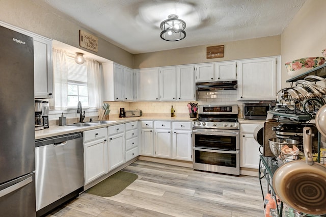 1908 Hazel St, Carthage, MO 64836 - kitchen with stainless steel appliances, under cabinet range hood, light countertops, white cabinets, and decorative backsplash