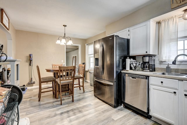 1908 Hazel St, Carthage, MO 64836 - kitchen with dishwasher, refrigerator with ice dispenser, white cabinets, light wood-style floors, and pendant lighting