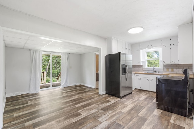 595 Johns Ford Rd, Sparta, MO 65753 - kitchen with stainless steel fridge, white cabinets, wood finished floors, decorative backsplash, and light countertops