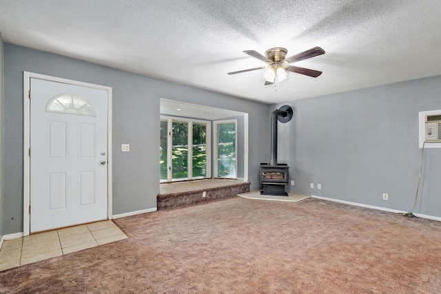 1311 S 9th St, Ozark, MO 65721 - unfurnished living room featuring carpet flooring, a wood stove, a ceiling fan, a textured ceiling, and a wall unit AC
