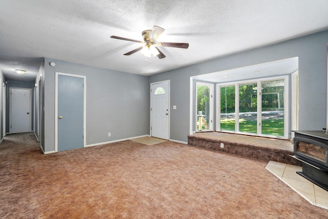 1311 S 9th St, Ozark, MO 65721 - unfurnished living room with a wood stove, carpet flooring, ceiling fan, and a textured ceiling