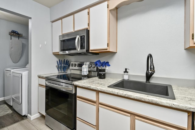 123 Bunker Ridge Dr Unit 7, Branson, MO 65616 - kitchen featuring stainless steel appliances, washing machine and clothes dryer, light countertops, and white cabinetry
