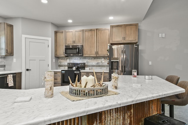 3918 Bowen Creek Rd, Niangua, MO 65713 - kitchen with stainless steel appliances, a kitchen bar, decorative backsplash, recessed lighting, and light stone counters