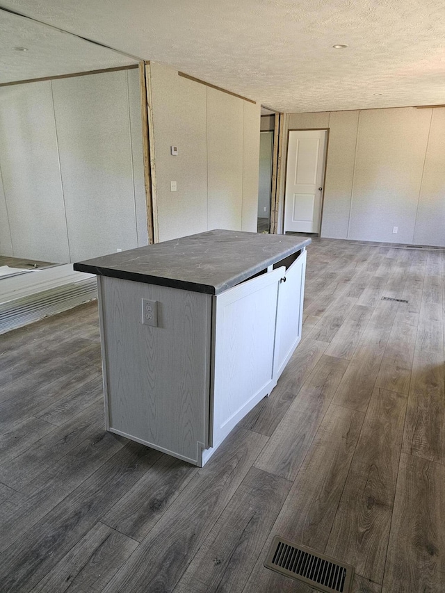 000 Oak St, Conway, MO 65632 - kitchen featuring wood finished floors, a center island, dark countertops, a textured ceiling, and white cabinets