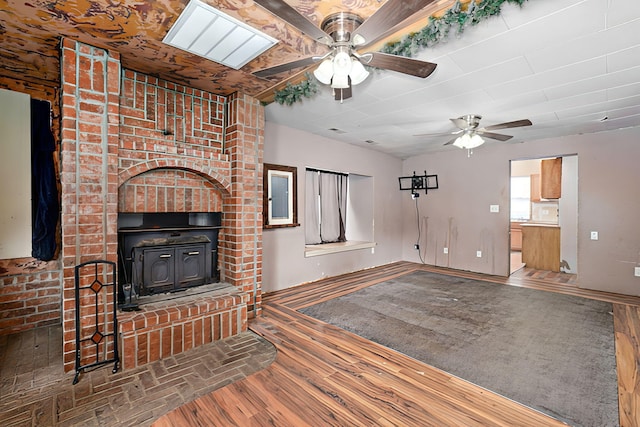 427 Morgan Ave, Aurora, MO 65605 - unfurnished living room featuring a ceiling fan, a wood stove, and wood finished floors