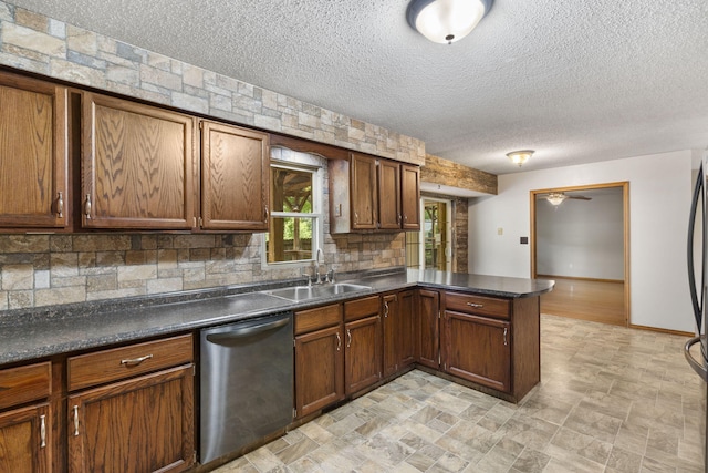 1801 W Cherokee St, Springfield, MO 65807 - kitchen featuring stainless steel dishwasher, a peninsula, tasteful backsplash, dark countertops, and a textured ceiling