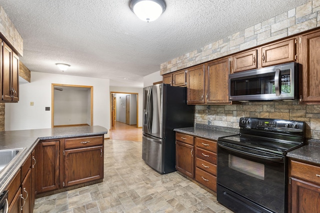 1801 W Cherokee St, Springfield, MO 65807 - kitchen with appliances with stainless steel finishes, dark countertops, tasteful backsplash, a textured ceiling, and stone finish floors
